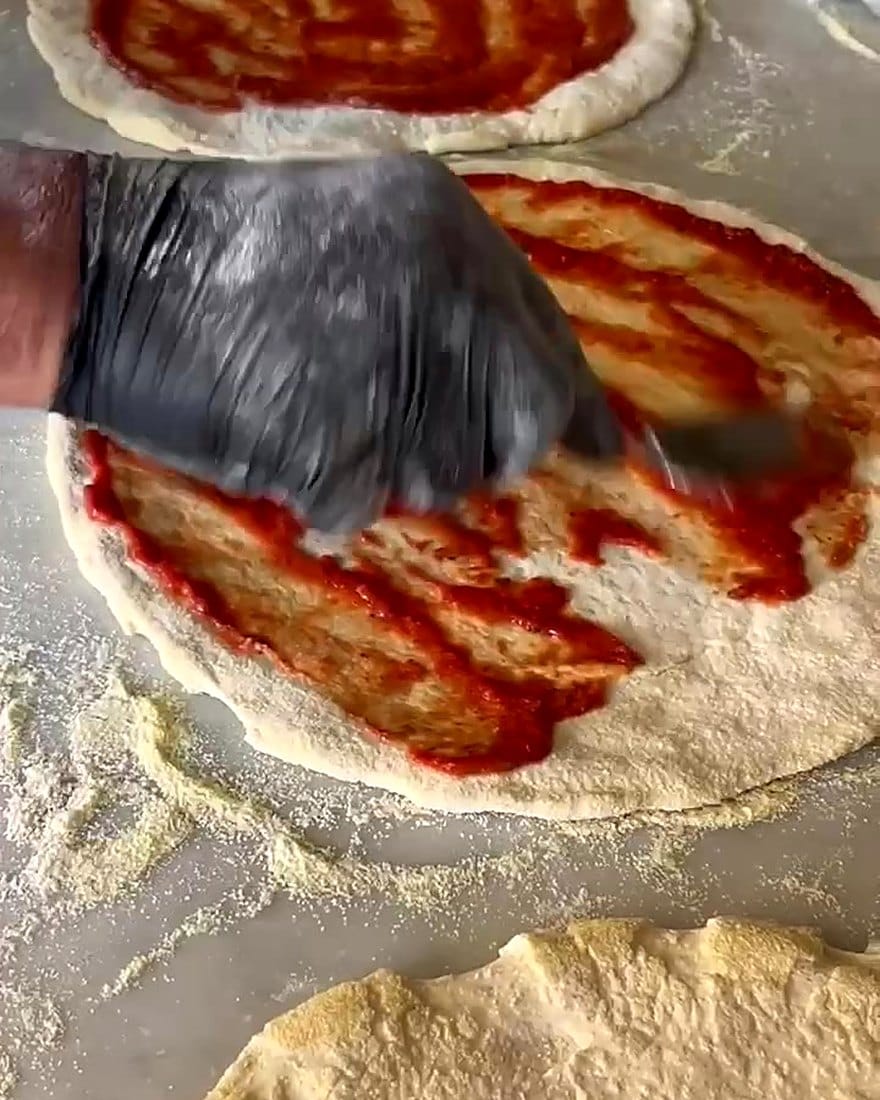 Flo garnit une pizza de sauce tomate dans son camion aux Issambres