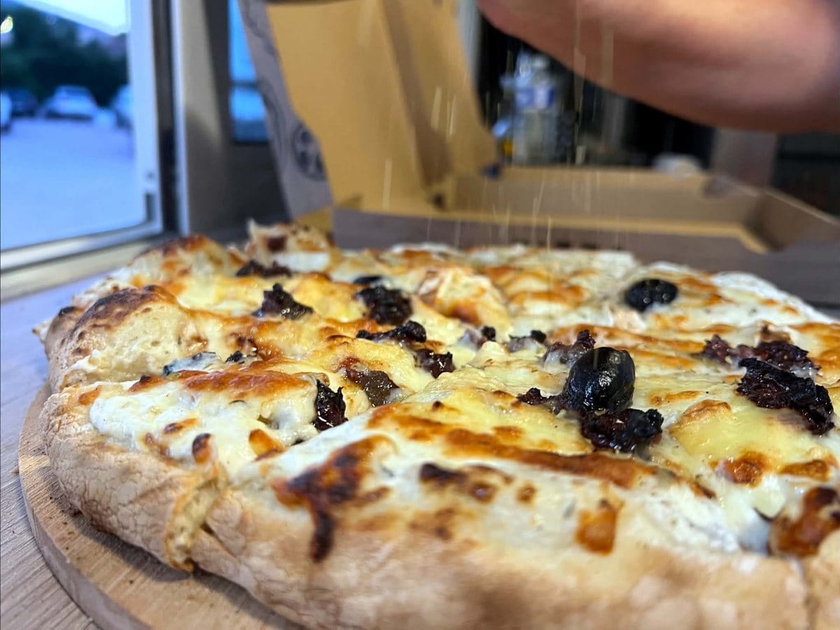 Pizza moiti&eacute; U Corsica, moiti&eacute; Biquette, sur une planche en bois